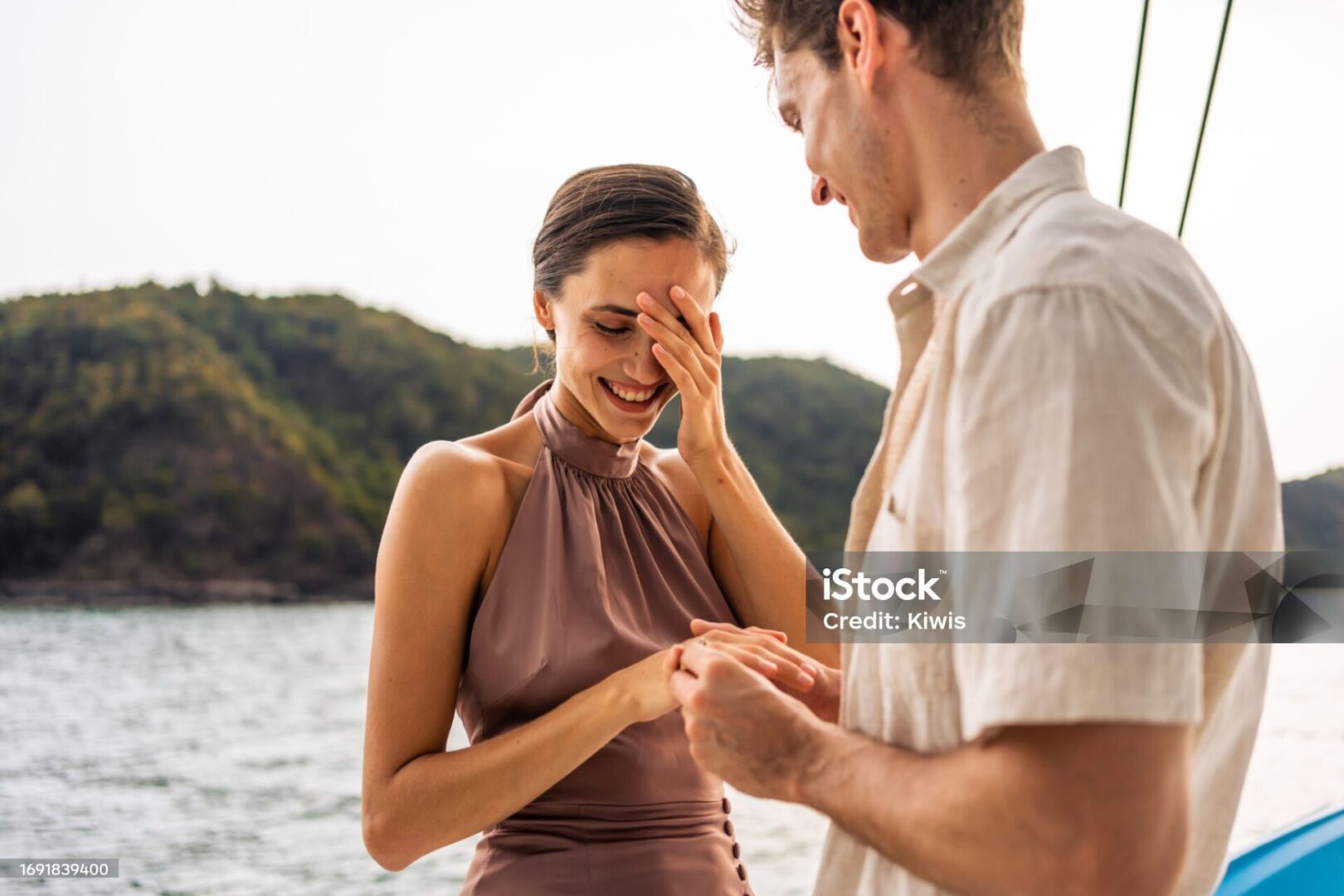 Caucasian young man make surprise proposal of marriage to girlfriend. Attractive romantic male proposing to beautiful happy woman with wedding ring enjoying surprise engagement while yachting together