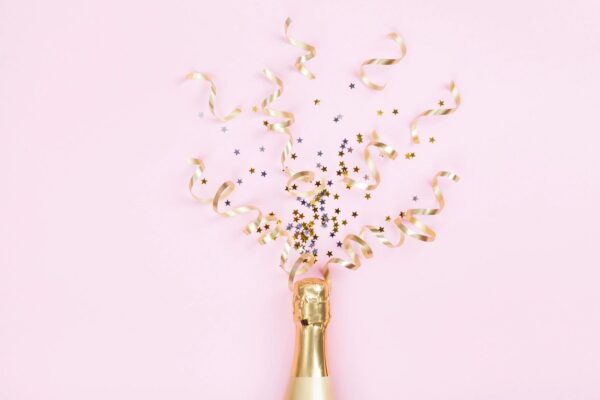 Champagne bottle with confetti and ribbons.